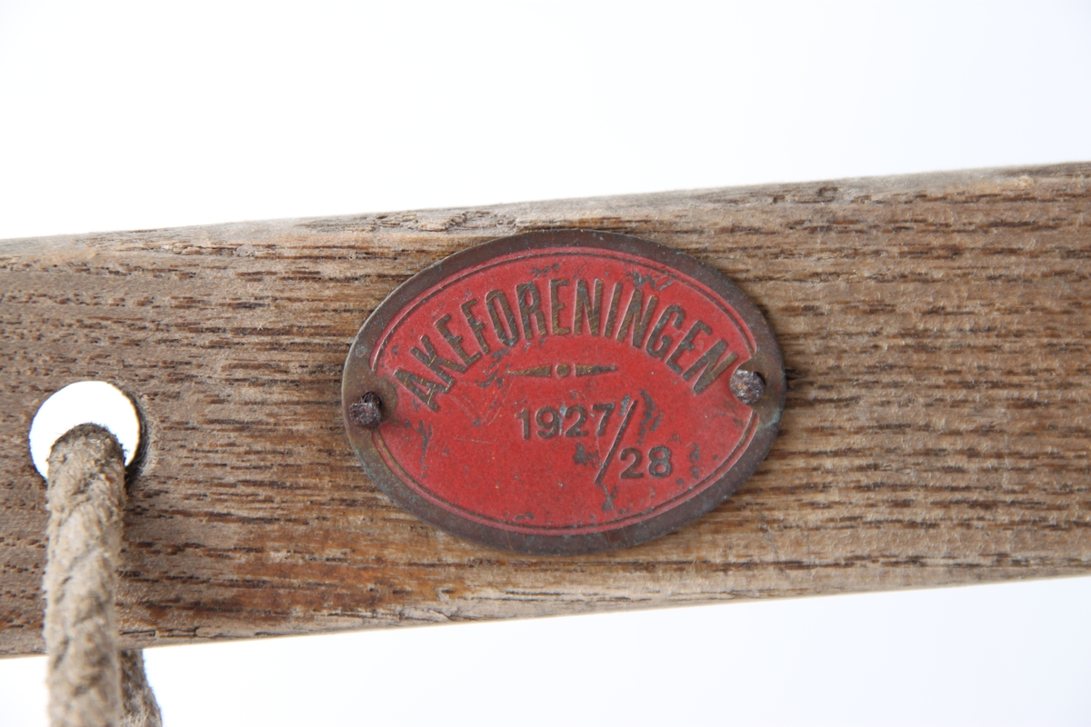 Kjelke med tau foran, og et skilt som sier "Akeforeningen 1927-1928". Kjelken brukes med styrestang.