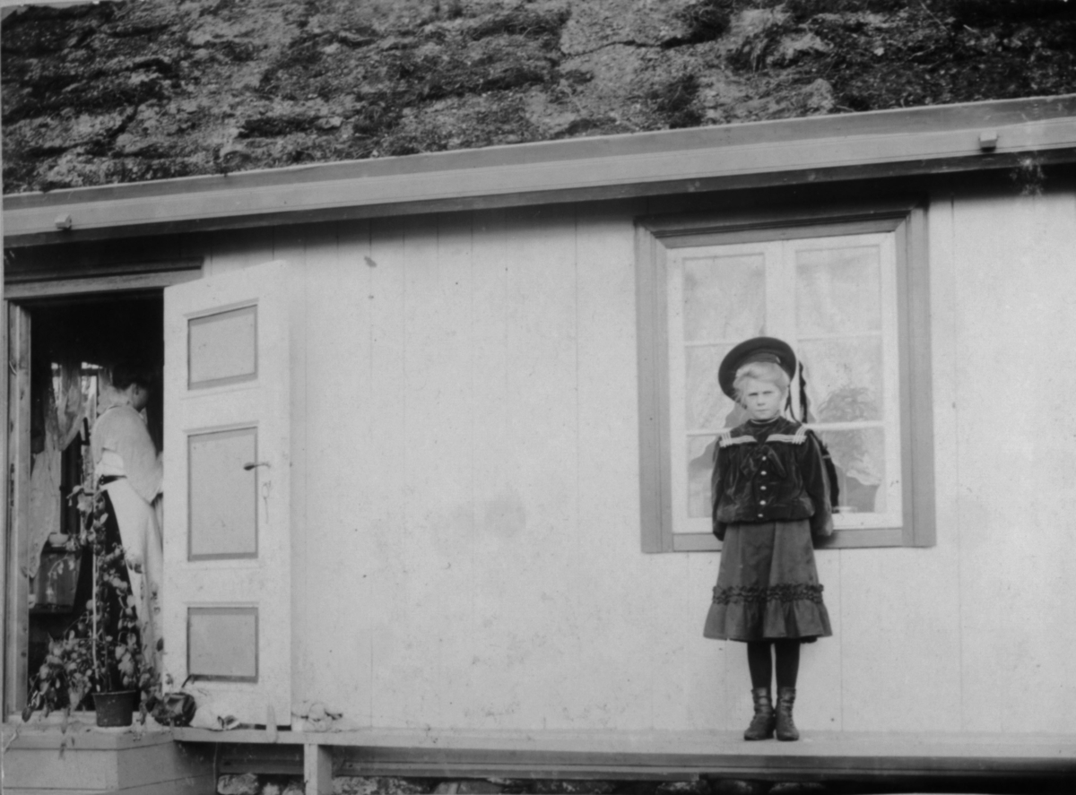 Frøken Dagmar utenfor Fossestuen 14.august 1967. I døråpningen ryggen av en dame. På trappen en plante.