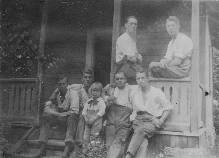Grupporträtt. Sex stycken män och en pojke vid en veranda, 1920-tal.