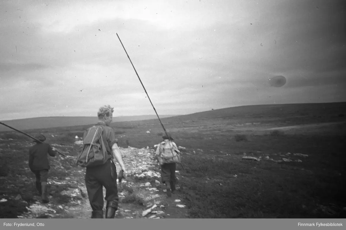 To menn på fjelltur i terrenget over Vadsø de har fiskestenger og ryggsekk. Bakerst Oluf Østbø