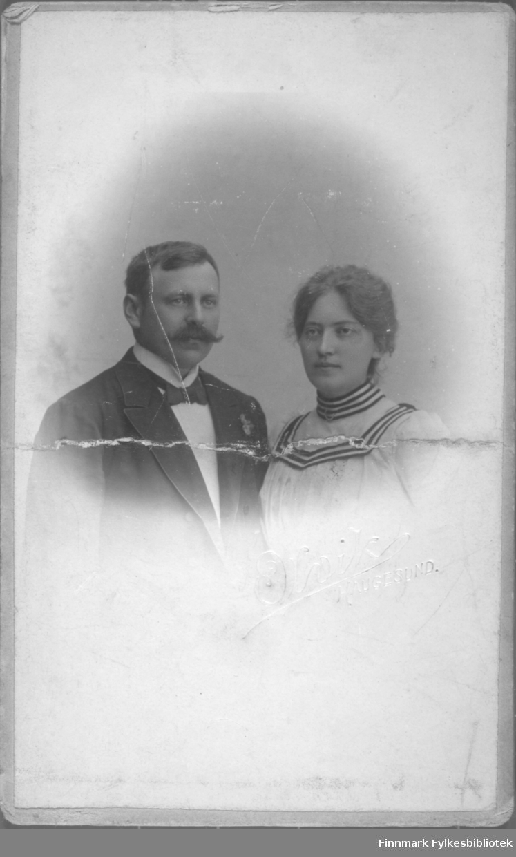 Portrett av en mann og en kvinne. Mannen har mørk dressjakke, hvit skjorte og slips på seg. Kvinnen har en lys bluse med mørke striper på kragen.