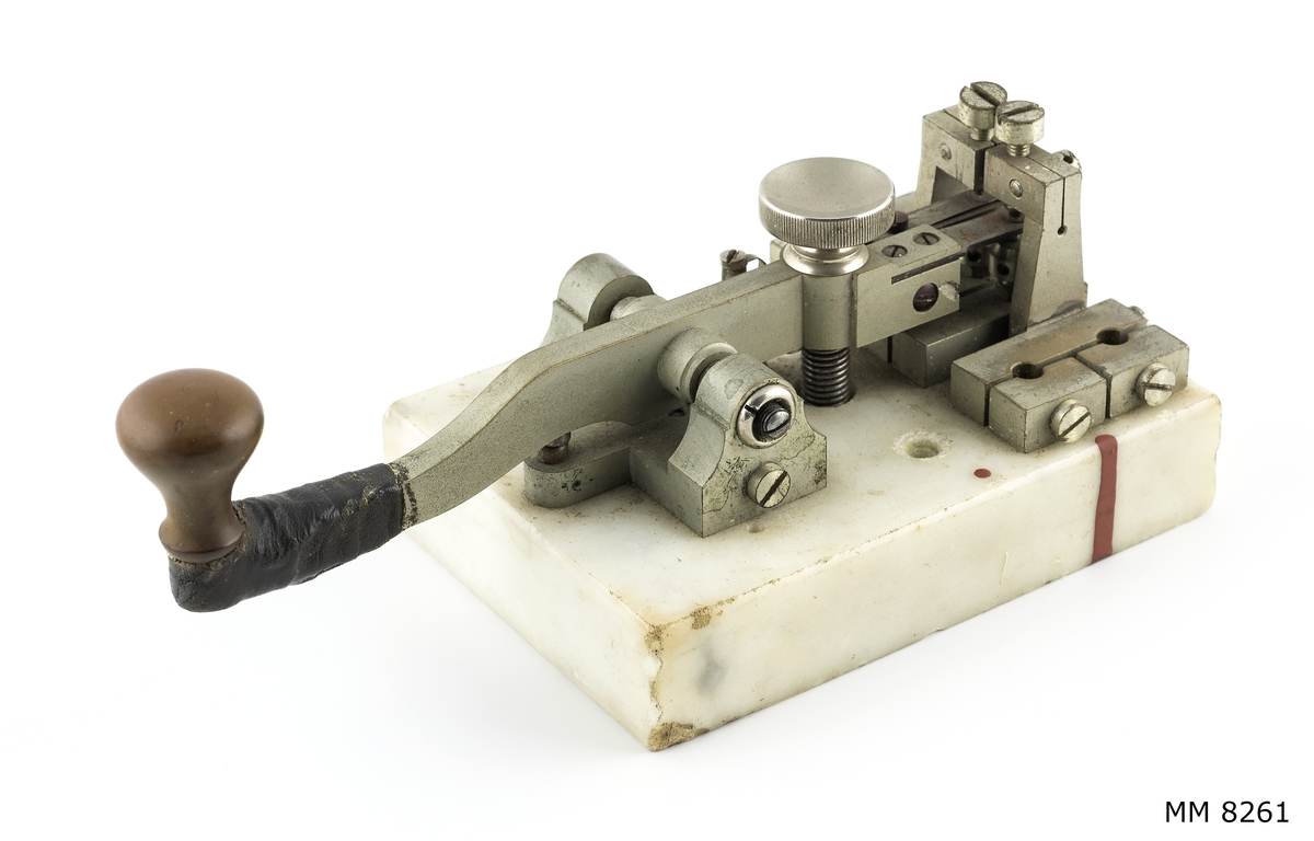 Telegraferingsnyckel av förnicklad metall monterad på en platta av marmor.
Tillhör 400 W kv-lv-sändare m/37 från u-båten Delfinen.