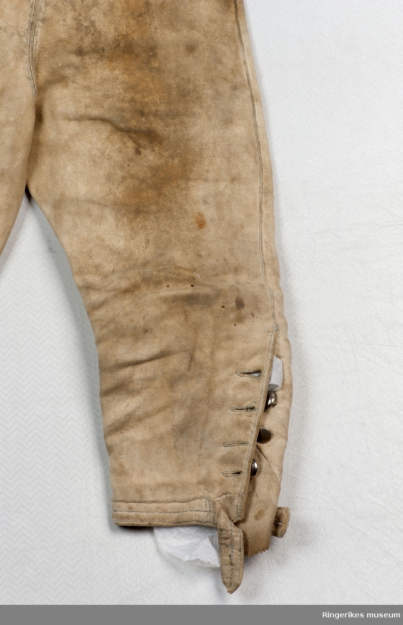 smale taggete kanter og markerte stikksømmer  på lommer og klaffer nedenfor knærne, lang stikksøm foran.