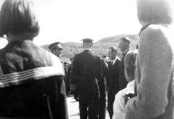 Fem menn i dresser og uniformer midt på bildet. De to til ve