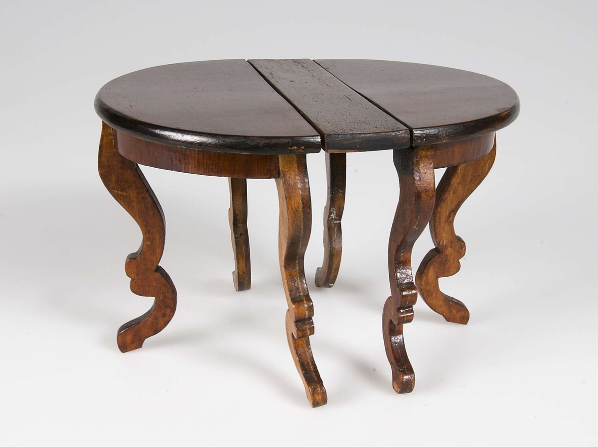 Matbord med svängda ben tillverkat av lackat trä. Till bordet finns en iläggsskiva.