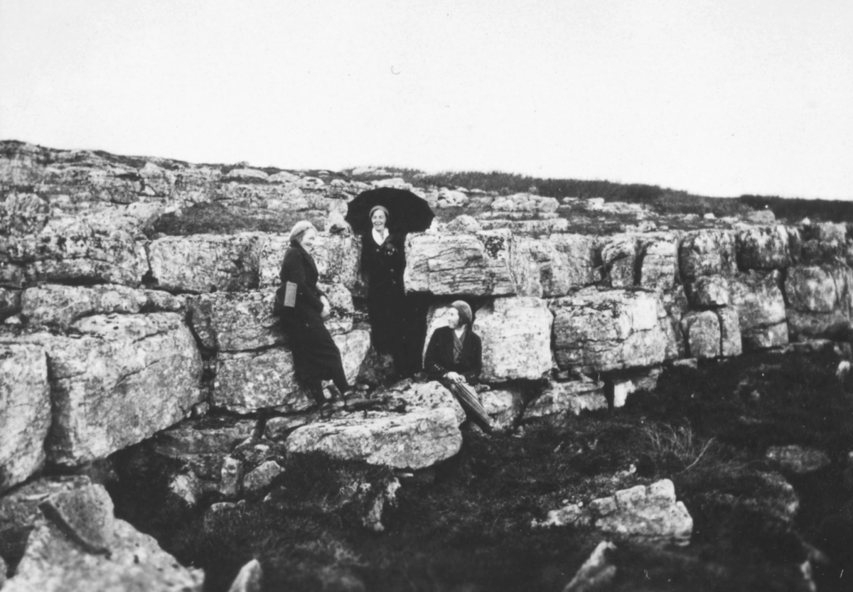 Tre personer som står på steinbergene. Dette er sansyneligvis på baksiden av Vadsøøya