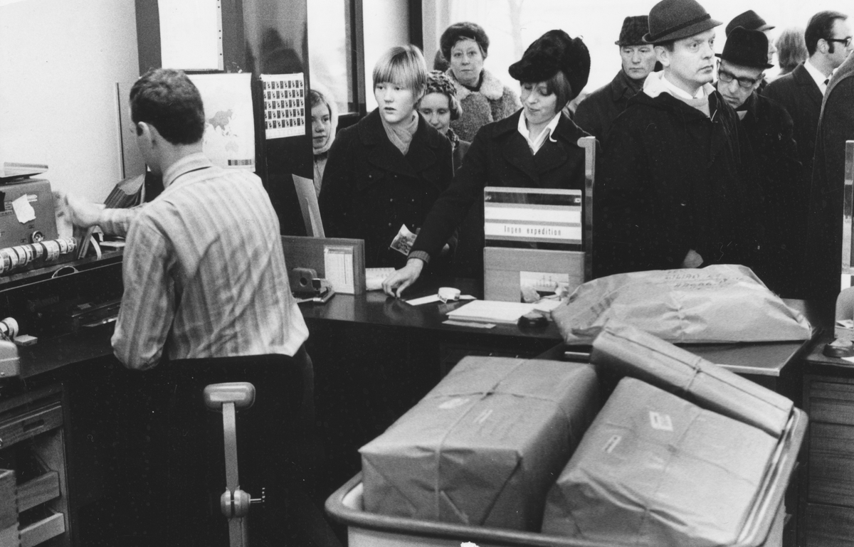 Julruschen på postkontoret Jakobsberg, 1969. Paket, frimärken, julkort, rek, postförskott - Åke Lindberg håller högsta fart för att "beta av" den till synes aldrig sinande kön.