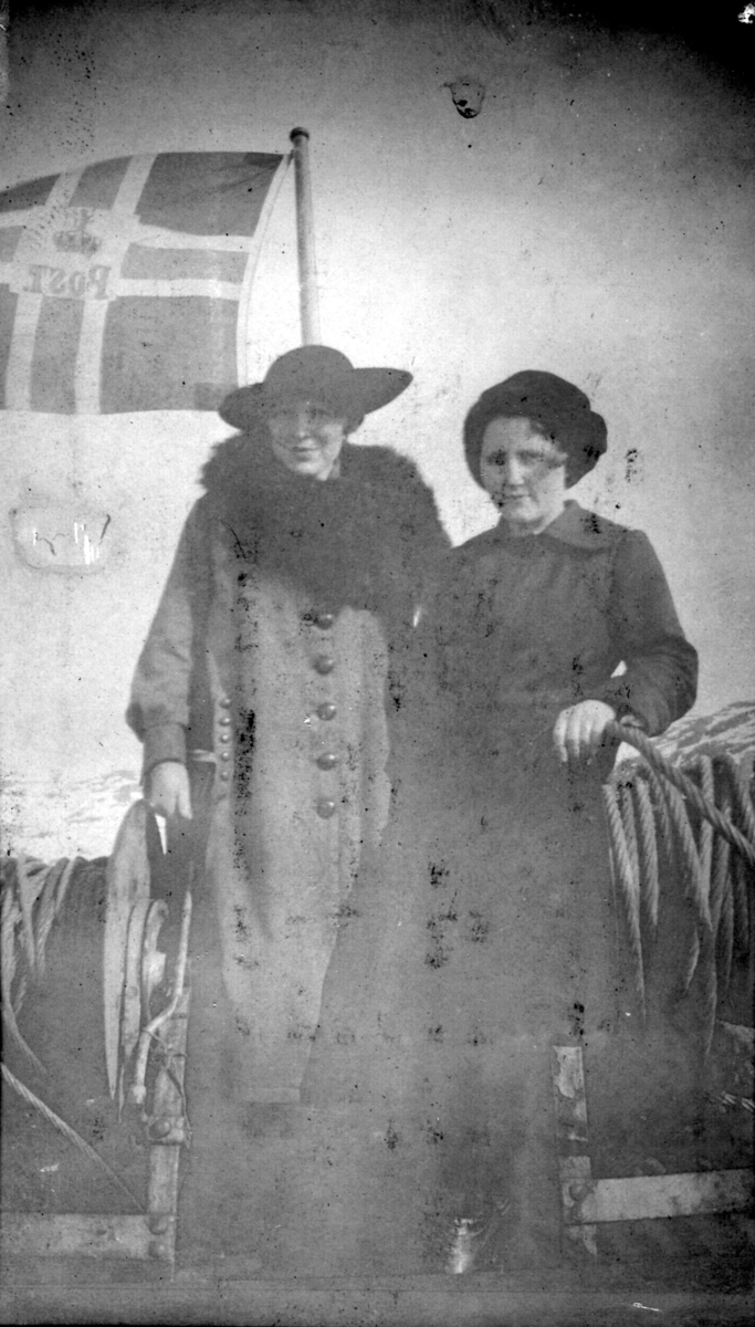 To kvinner om bord i MS "Varanger" 1918. Kvinnen t.h. kan være lærer Ragna Sofie Hansen. Kvinnene er kledd i tykke kåper. Kvinnen t.v. har en pelskrave rundt halsen og en hatt på hodet.
