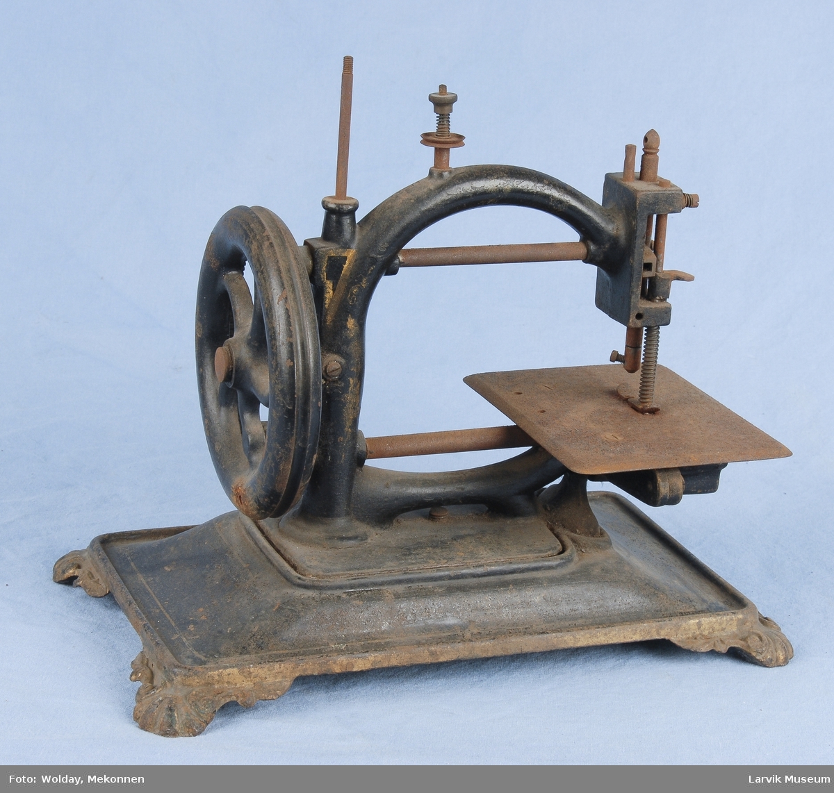 Form: maskinen står på en plate av jern med 4 føtter med skjelldekor/sveiv av tre/2 tannhjul av messing