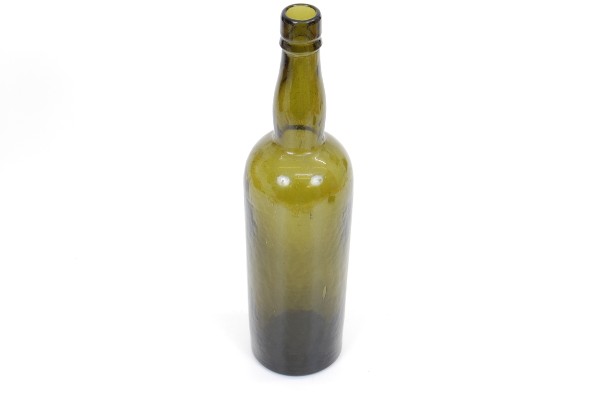 Form: Høy flaske med sirkulær grunnflate, rette vegger og lang hals. 
