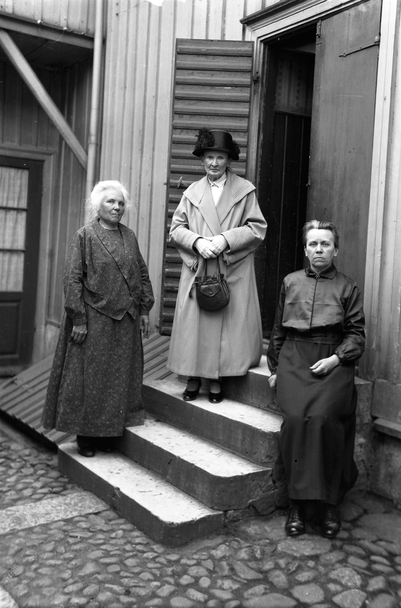 Tre äldre damer på en bakgård.
