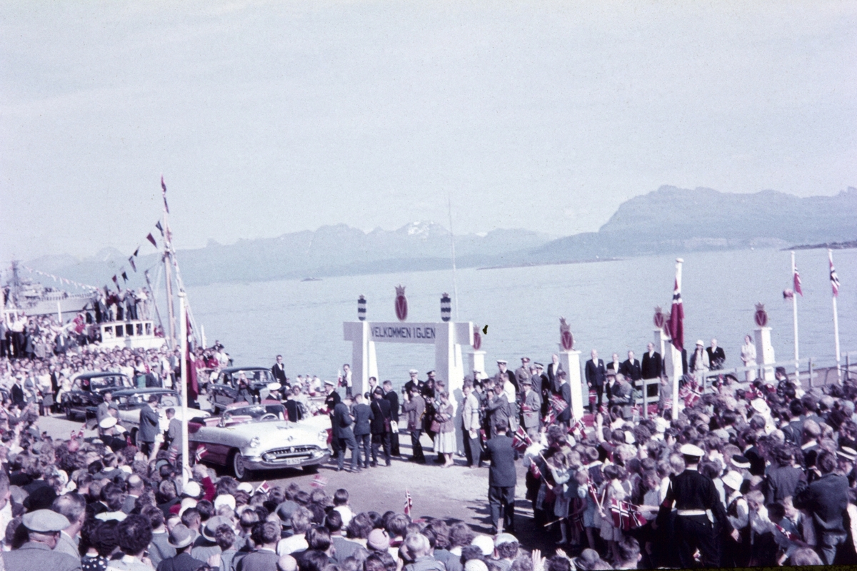 Folkemengde på kaia tar i mot (eller tar farvel) med kongen. Biler til venstre.