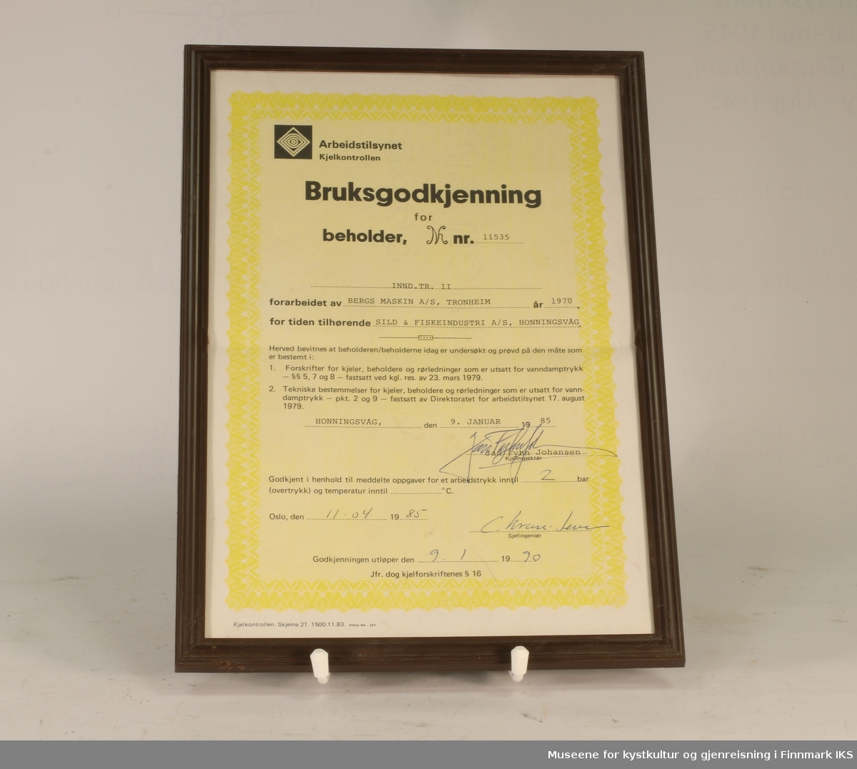 Bruksgodkjenning for INND. TR. II (beholder nr. 11535) hos Sild & Fiskeindustri AS, utsendt av Arbeidstilsynet Kjelkontrollen i 1985. Hvitt og gult papir med sort tekst. Utfylt for hånd. Innrammet.