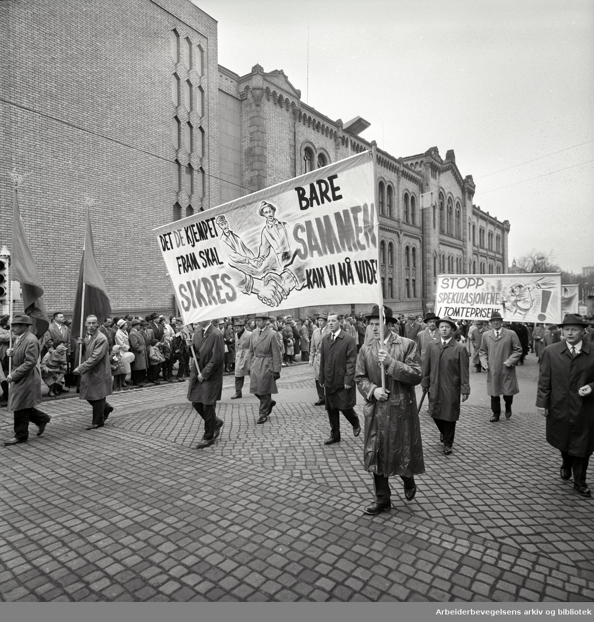 1. mai 1963 i Oslo.Demonstrasjonstoget i Karl Johans gate..Parole: Det de kjempet fram skal sikres.Bare sammen kan vi nå videre.Parole: Stopp spekulasjonene i tomteprisene!