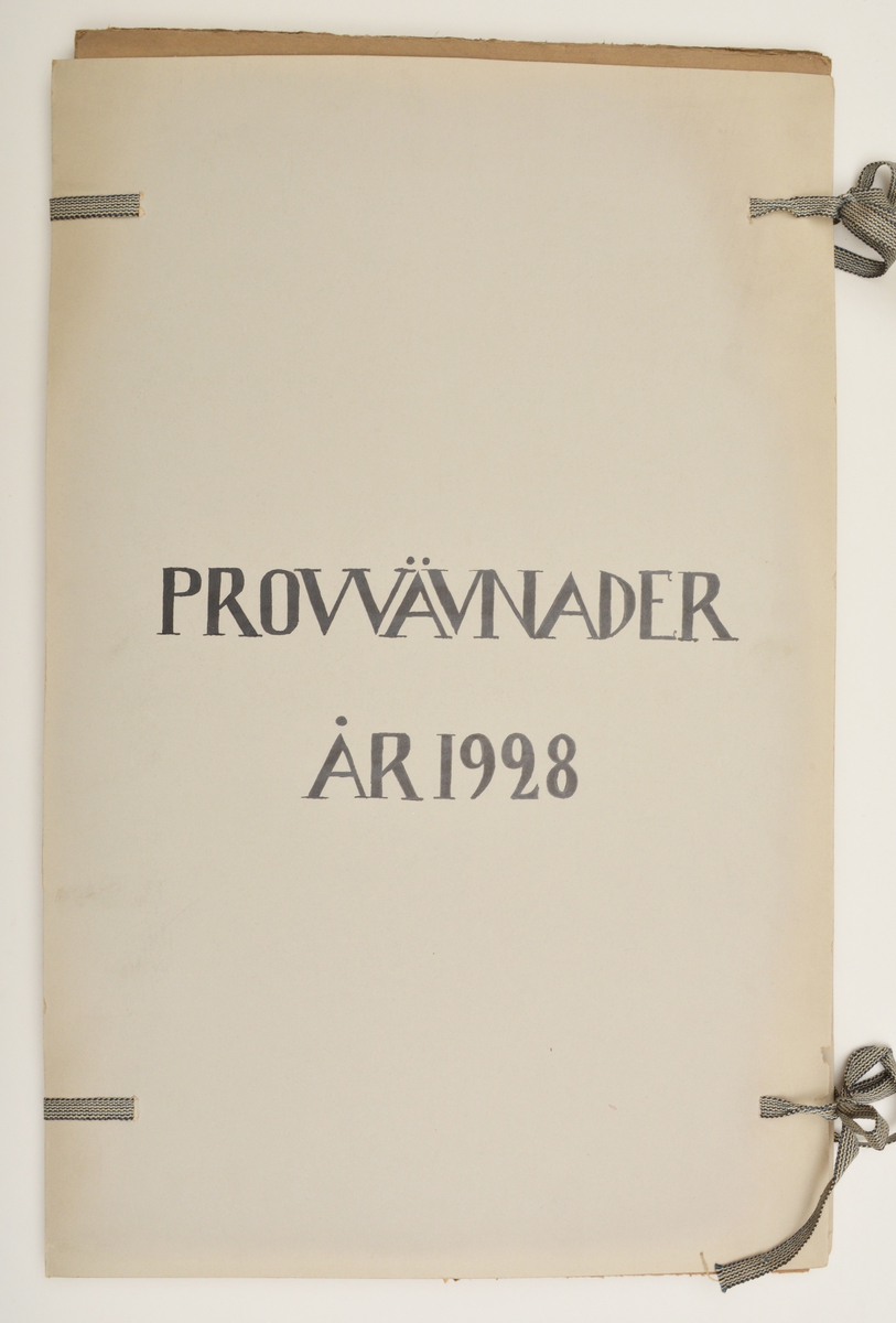 Stor pappersmapp med lösa blad med påklistrade tygprover. Pärmarna är av en annan papperskvalité än papperna innuti. Pärmarna hålls ihop med ett par långa, handvävda band.
Text på framsidan; "Väfprofer År 1928".