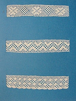 Blått kartongark med tre prov på knypplad skånsk spets från östra Göinge härad. Vid varje prov står en stor bokstav. 
A. 13 x 2,5 cm
B. 13 x 2,5 cm
C. 13 x 2,8 cm