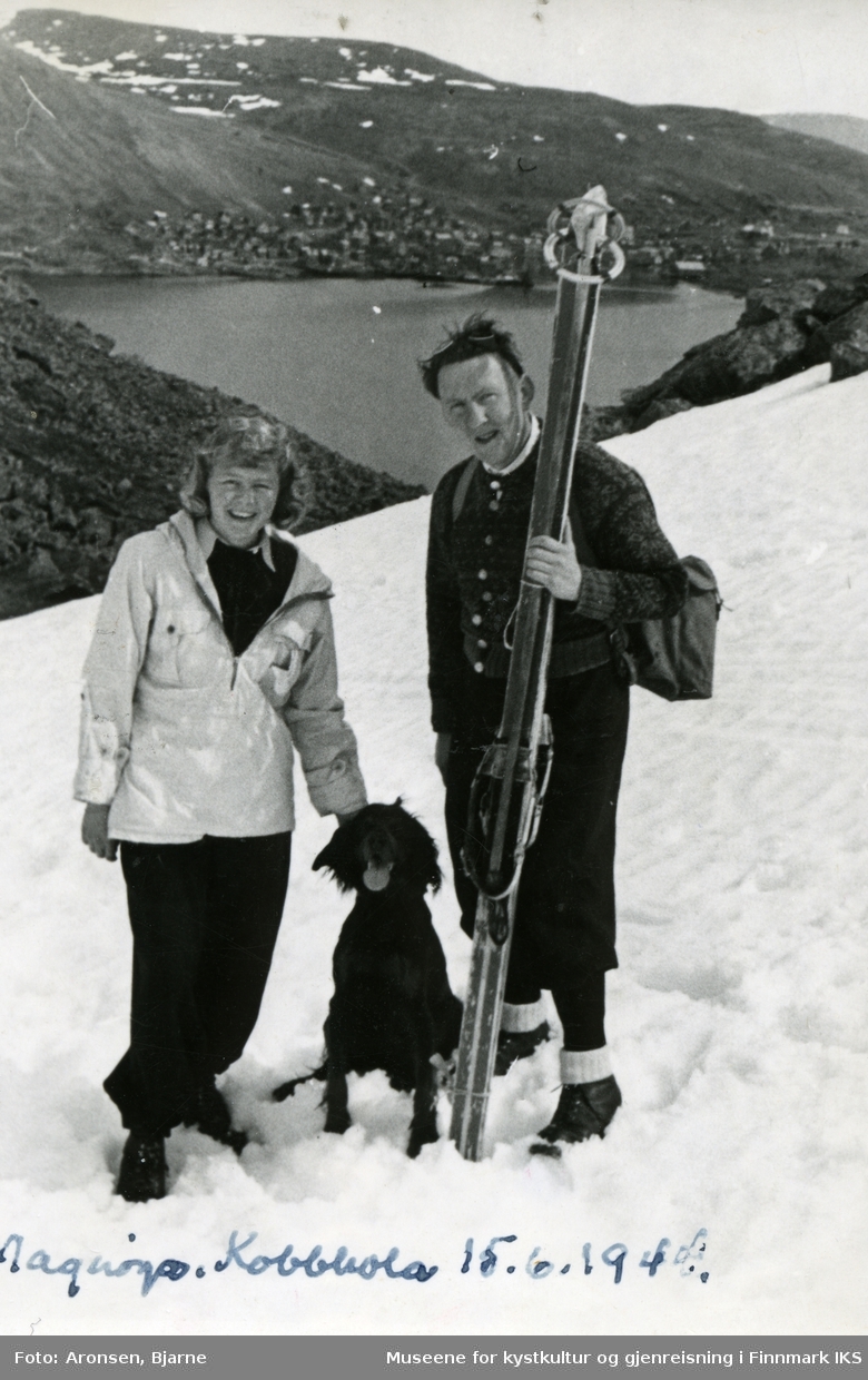 Gyda Aronsen, hunden og prest Ola Røkke på skitur i Kobbholet. I bakgrunnen ser man Honningsvåg. 15. juni 1944.
