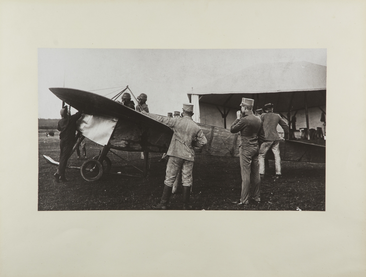 Flygplan M 1 Nieuport vid Axvalla hed. Militärer kring flygplanet. I förarsits sitter Gösta von Porat. Till höger i militärklädsel står Allan Jungner.
