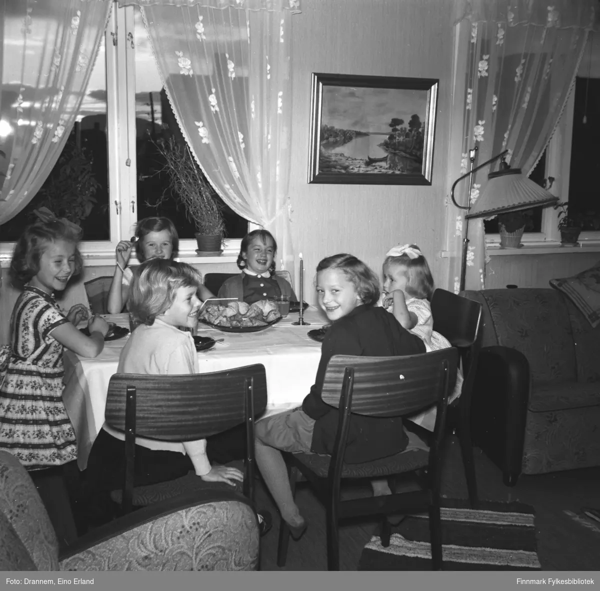 Fem jenter på bursdagsselskap hos Turid Lillian. Jentene sitter ved bordet i stua og spiser kaker og drikker saft med sugerør