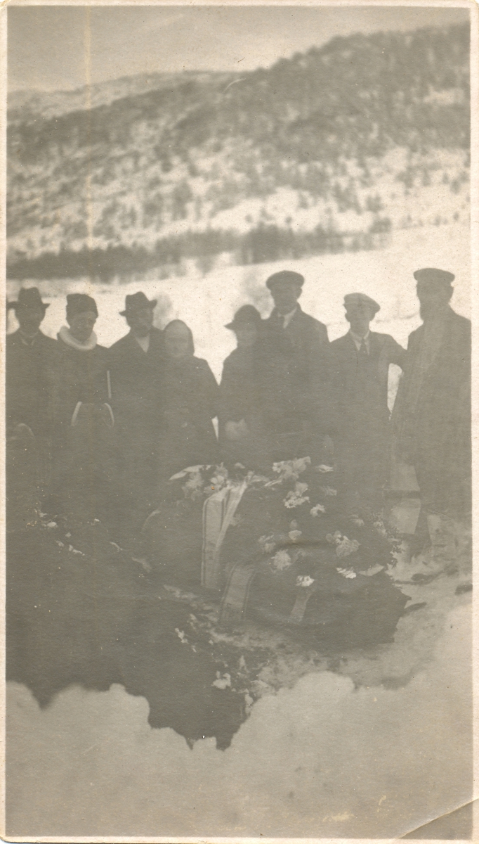 En gruppe mennesker ved ei kiste under en begravelse.