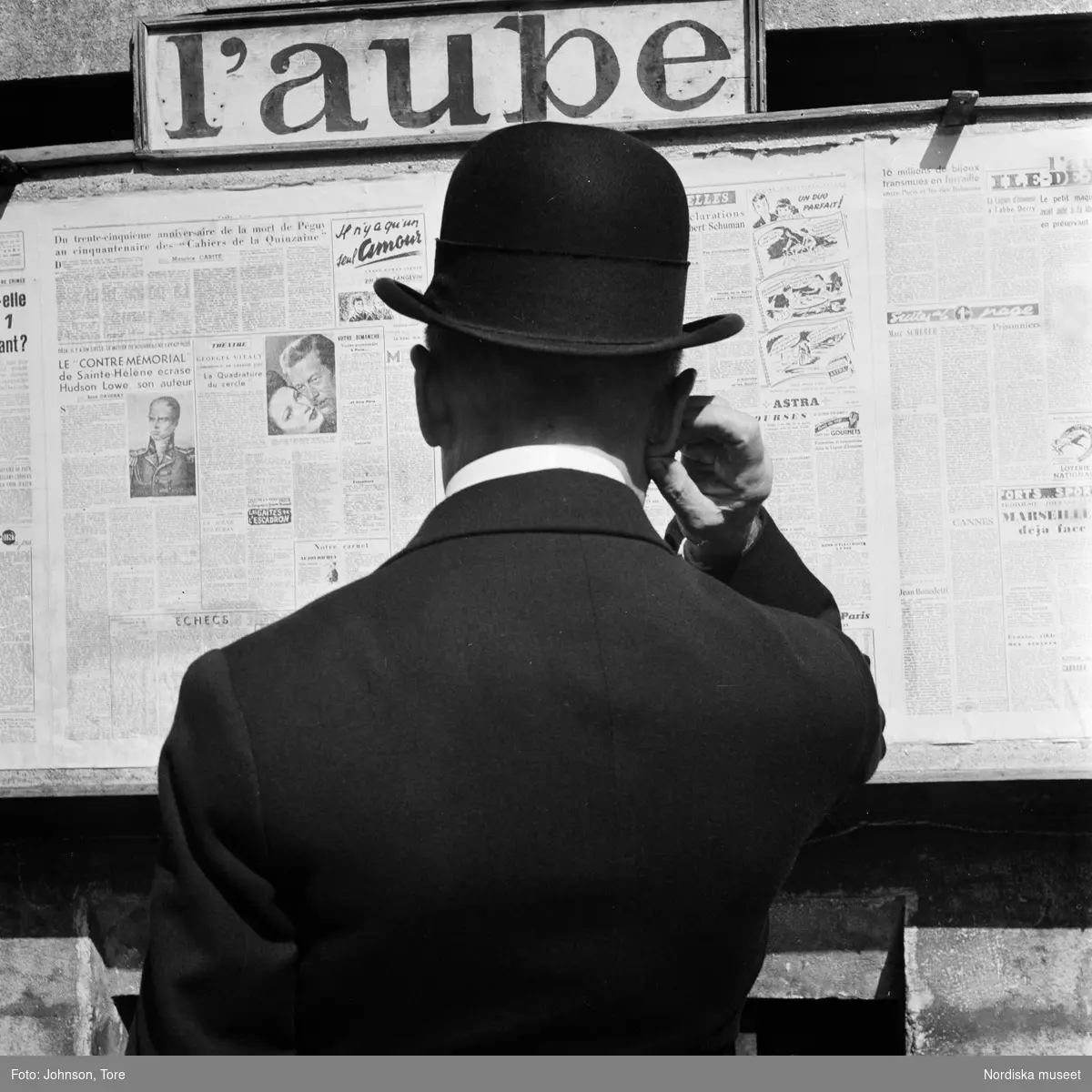 Paris. En man i plommonstop läser anslag med tidningen "L'Aube".