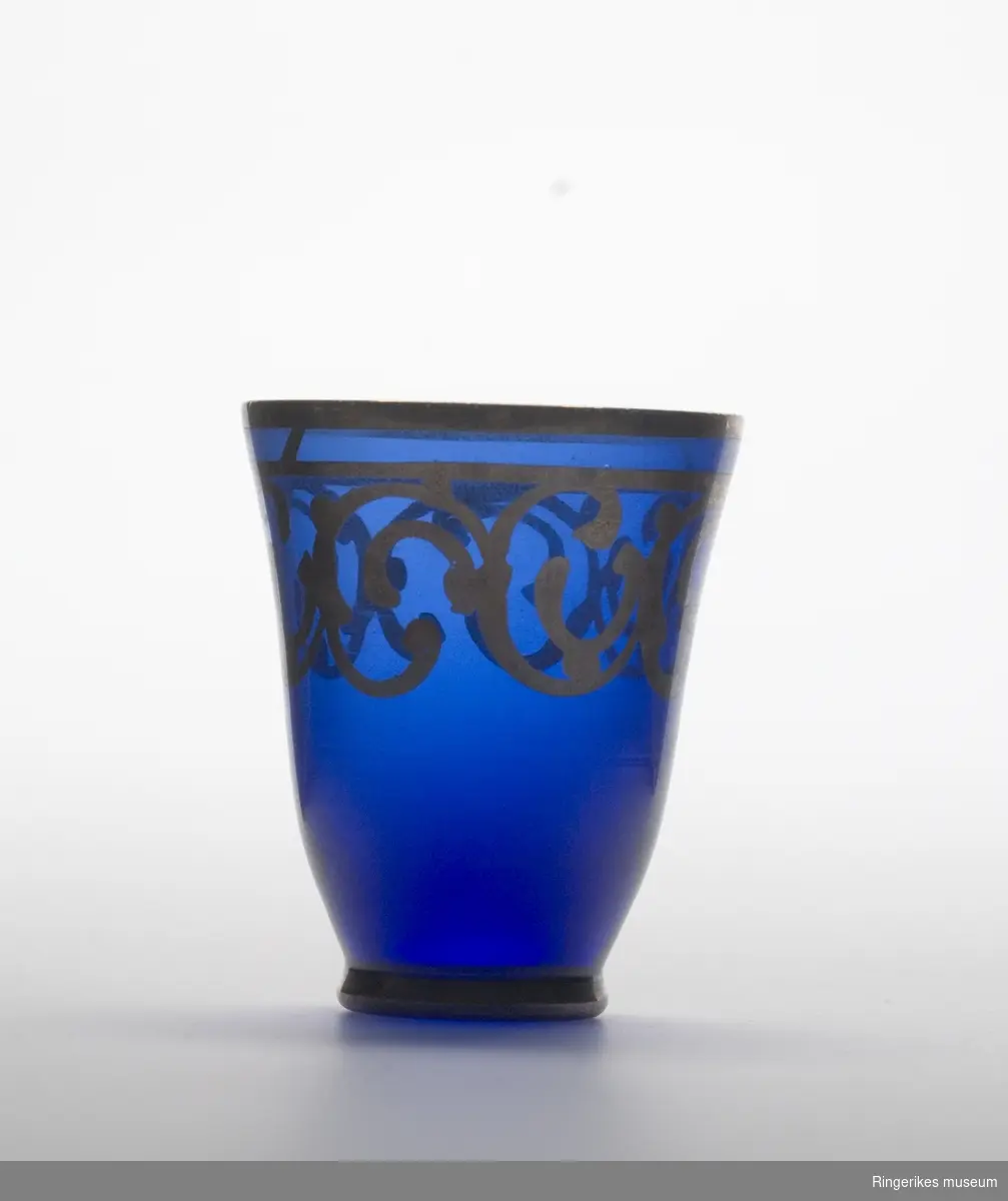 Drammeglass i blått glass med gulldekor.
Et sett som inneholder karaffel og åtte glass.