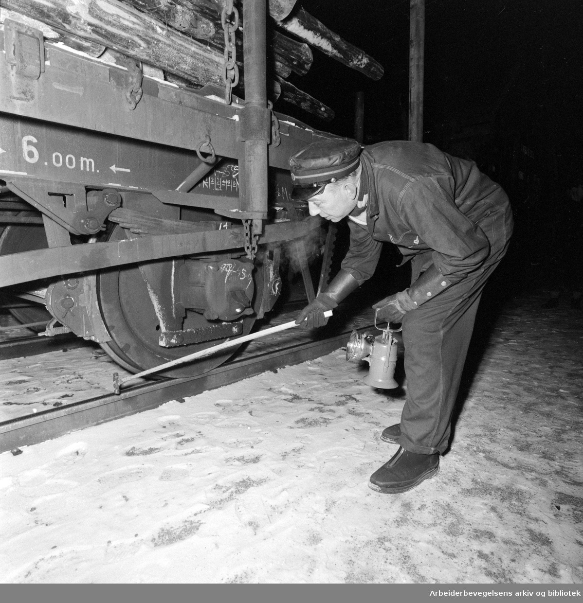 Vognvisitør Karl Brockstedt i NSB sjekker hjulene på en godsvogn. Februar 1960.