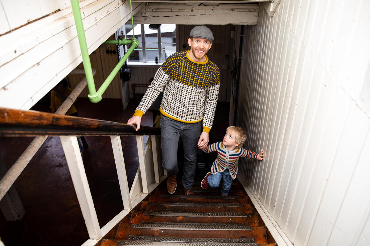 Mann og barn går opp trapp i fabrikklokale