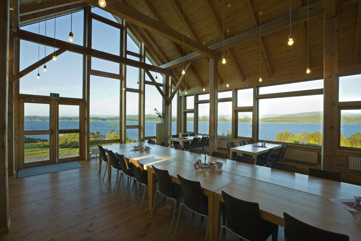 interiør med langbord, vindauge med utsikt over kystlandskap