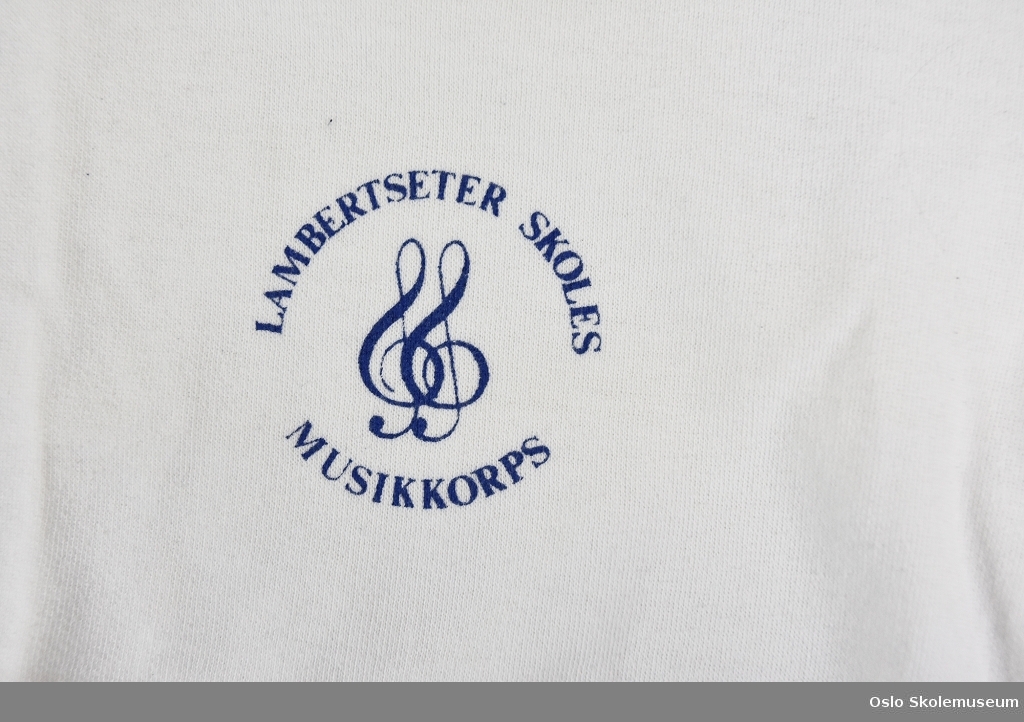 Hvit aspirantgenser fra Lambertseter skoles musikkorps til barn. Genseren har korpsets emblem på venstre bryst.
