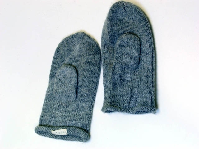 Ett par stickade tumvantar i grått ullgarn. Vantarna har varit utställda i basutställningen "I barnaminne" på Landskrona museum. Utställningen stod mellan 1989 och 2007.