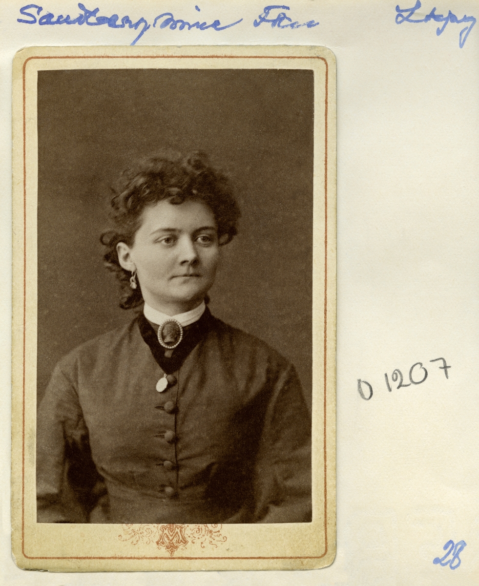 Porträtt av fröken Sofia Wilhelmina ”Mina” Sandberg. Född 1846 i Linköping som dotter till auktionsvaktmästare Per Gustaf Sandberg och Anna Helena Wigholm. Förblev ogift och levde med sin mor fram till sin död i sviterna av tuberkulos den 6 november 1887.