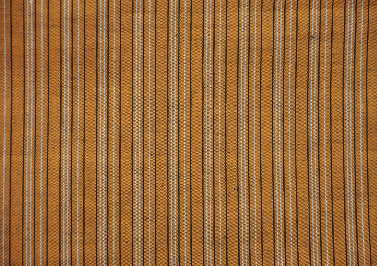 Bomullstyg, 1930-talet
Långrandigt bomullstyg.
Gult-svart-vitt
Garnfärgat gult inslag.
Otvinnat garn.
Rapport -- x 2,8 cm