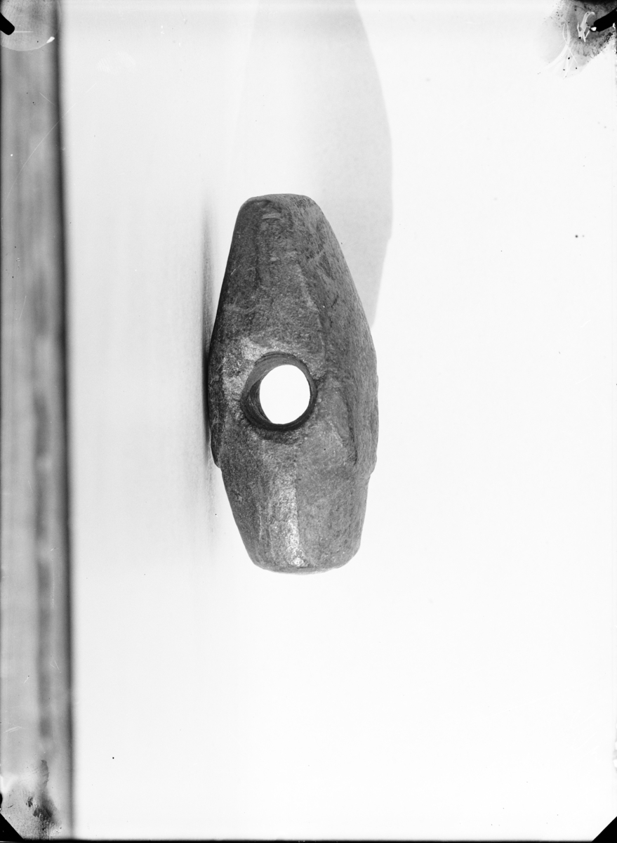 Stenøks med skafthull av klebersten, nærmest å sammenstille med Minnen 334, men ikke med så sterkt fremtredende relieff og med bredere buer enn på nevnte eksemplar. Eggen er butt. Lengde 8,5 cm., største bredde over skafthullet 3,7 cm. 
