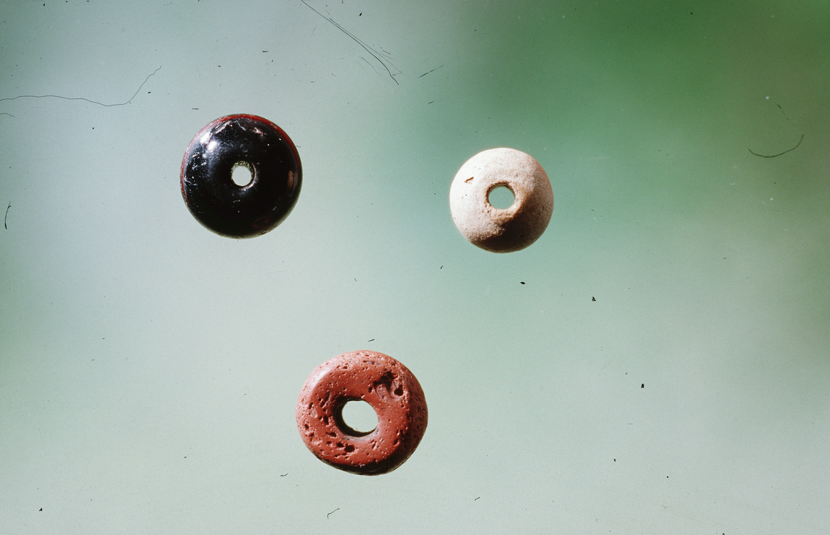 Tre perler av rød, svart og elfenbensfarvet glasfluss, diam. 9 og 12 mm. (Fnr. 2, 34, 58)