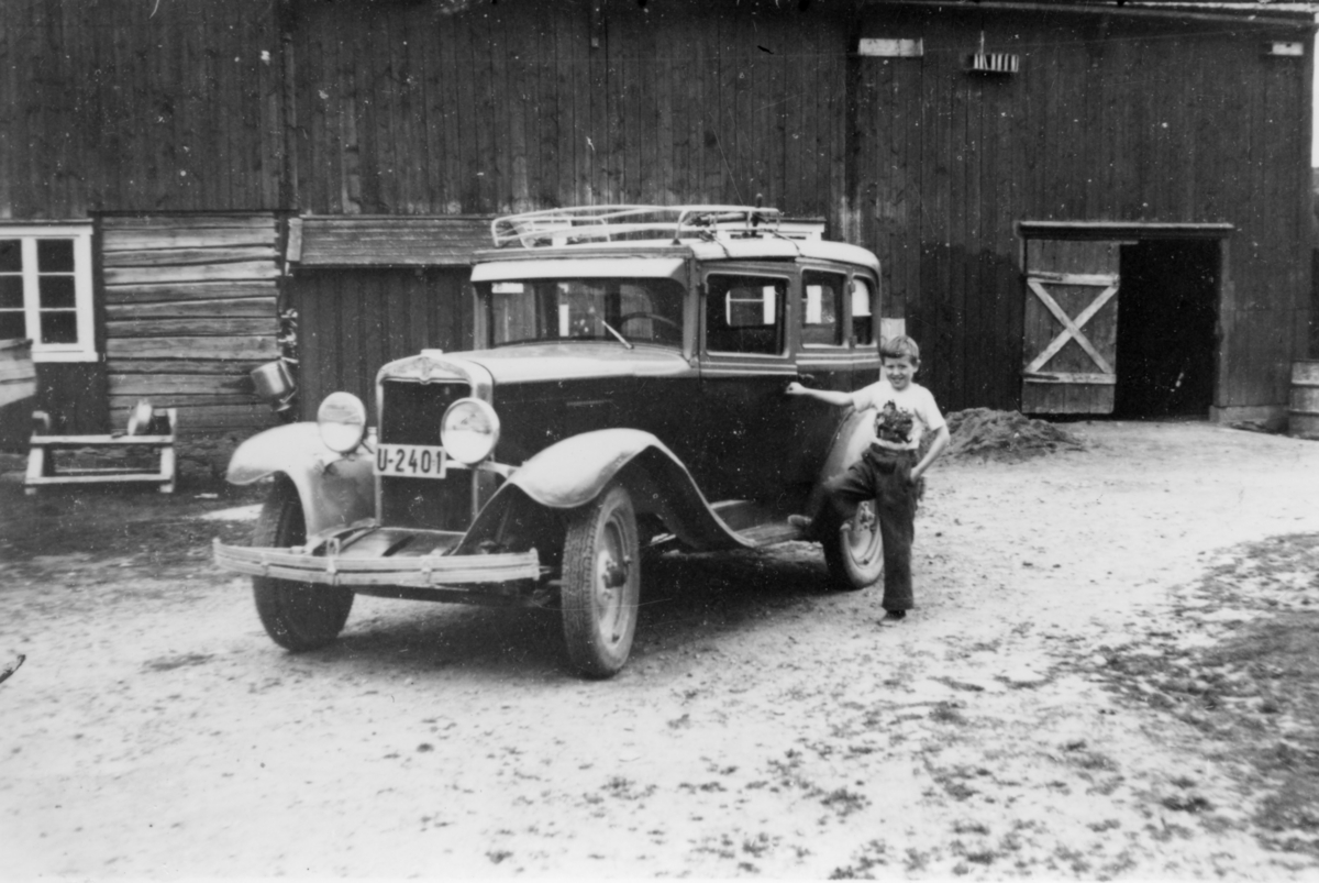 Postbil (Chevrolet) med liten gutt ved siden av bilen.