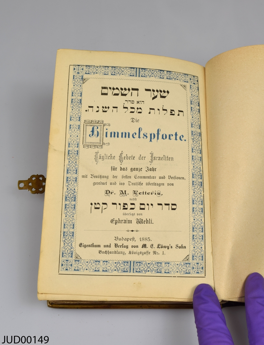 Siddur med skinnrygg och hård benvitt omslag dekorerat med elfenben- och mässingsbeslag. Boken är skriven på tyska och hebreiska. Boken är tryckt i Budapest 1885.