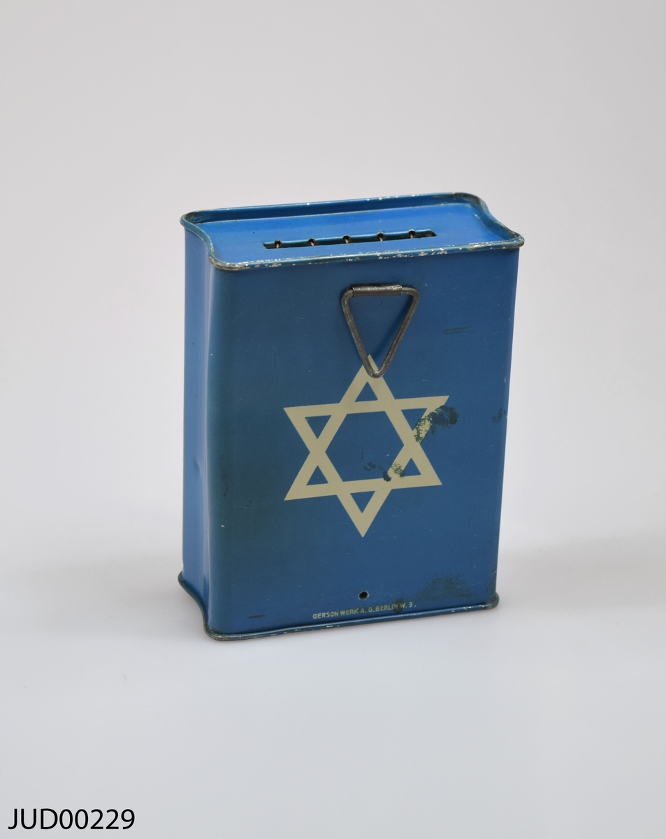 Insamlingsbössa, tillverkad av plåt som sedan målats blå med benvit dekor. Dekorerad med hebreisk text, Davidsstjärna samt "J.F"
