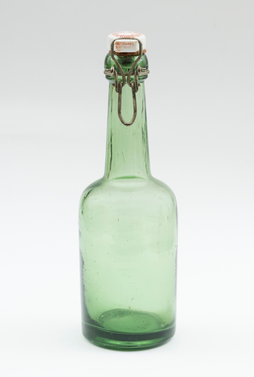 Flaske av grønt glass, antakelig opprinnelig brus- eller ølflaske, som kan ha vært gjenbrukt til aldre drikkevarer, for eksempel husholdningssaft. Flaska er 20,0 centimeter høy (uten kork). Den har en sylindrisk kropp med cirka 6,9 centimeters diameter. Cirka 10 centimeter fra standflata går den sylindriske delen over i ei innoverskrånende skulder mot en mer sylindrisk hals. Den midtre delen av flaskebotnen er oppoverkuvet. Flaska kan romme cirka 3 desiliter væske. Godset omkring munningen - «flasketuten» - er noe tjukkere enn i flaska for øvrig, og her er det et spor som har gitt feste for en såkalt «patentkork». Dette er en propp, utført i kvitt porselen, som er hengslet til flasketuten ved hjelp av ståltråd, som er forankret i det nevnte sporet omkring flasketuten slik at proppen faller ned i flaskemunningen og kan låses der ved hjelp av ei ståltrådspenne, som når flaska lukkes omslutter en tapp i den fremre enden av porselenselementet. Undersida av denne komponenten har vært utstyrt med en rødfarget gummipakning, som skulle skape et vakuum i flaska. Her er pakningen bare delvis intakt. Oversida av porselenselementet er merket «ELVERUM BRYGGERIs Mineralvandfabrik» (jfr. fotografiet SJF-F.013394).
