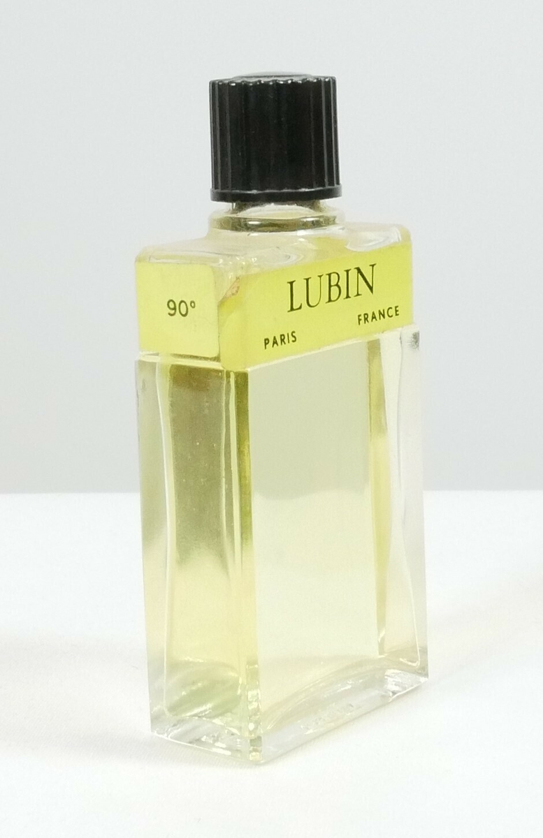 Rektangulær klar glassflaske med en svart rund plastkork. Øverst er det en påklistret gul etikett. Flasken inneholder en gul væske. 

Påskrift, etikett: 
GIN FIZZ // 90 // LUBIN // PARIS FRANCE // LUBIN