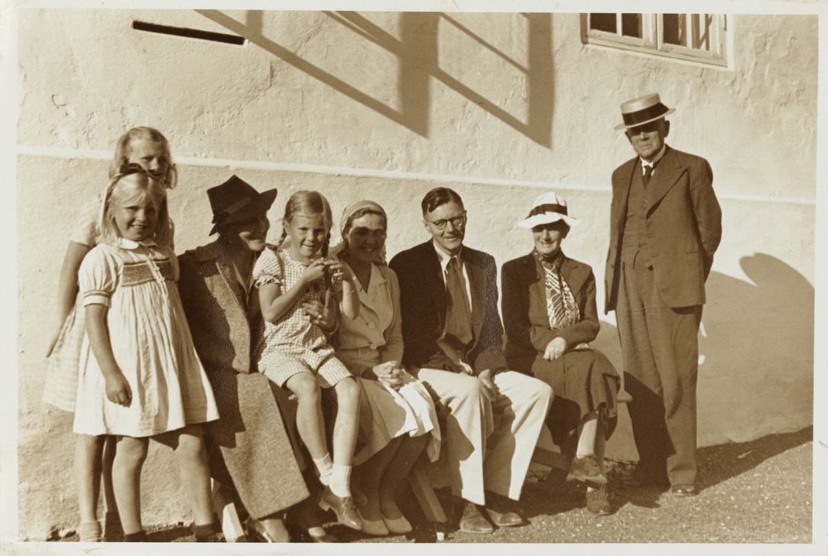 En gruppe barn, kvinner og menn fotografert foran storgården Hovinsholm i Hedmark..Blant dem er Kitty Hoel på fanget til Kitty Skjelderup, Sisken Skjelderup Hoel, Jacob Hoel, Nini Egeberg og Arthur Skjelderup. Fotografert september 1942.