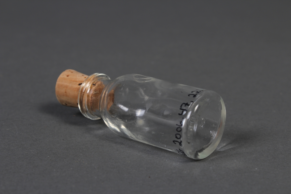Liten flaske i klart glass, med kork.
Gjenstanden har vore brukt i samband med dyrlegearbeid på Jæren.