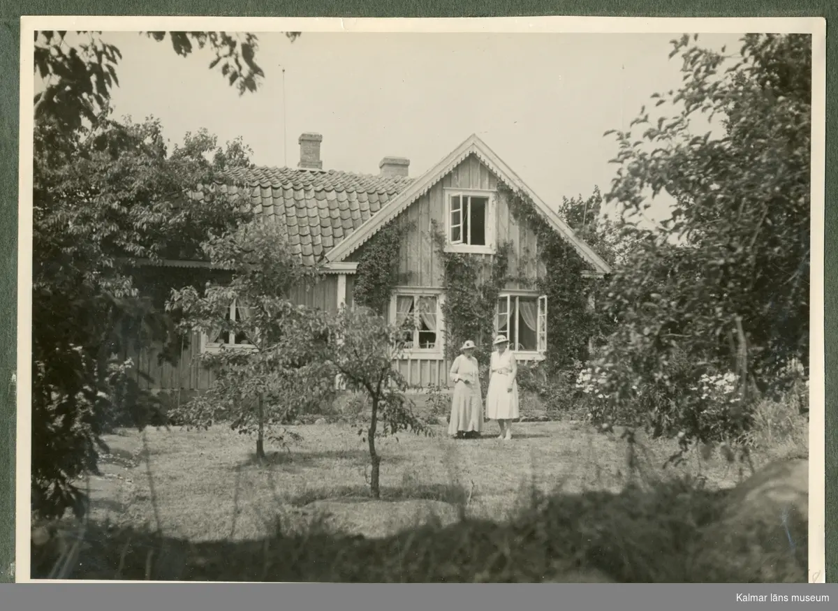 Svart-vitt fotografi som föreställer ett hus, framför huset står två kvinnor i trädgården. Troligtvis Karin och Ragnar Swahns sommarbostad på Stångudden, Ekenäs.