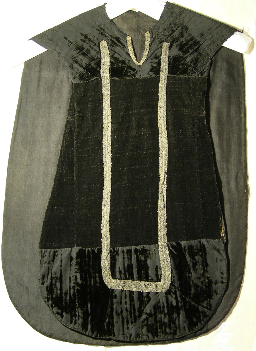 Slät sammet, svart.
Varp: svart silke
Polvarp: svart silke
Inslag: svart silke
Yllefoder i liksidig kypert (2/2), gråsvart. Tidigare foder, alternativt mellanlägg, i linne, 3-skaftad kypert (2/1), oblekt.
Mässhaken har axelsöm och en del av yttertyget mitt fram är av grövre ylle?sammet.
På framsidan 840 x 220 mm U-formad dekor av 2 spetsar i metalltråd (spunnet lan, silver) tillsammans 37 mm. Halsringning samt 110 mm djupt sprund med 15 mm bred spets i metalltråd (spunnet lan, silver).

På baksidan 1070 x 520 mm stort kors med konturer av 2 spetsar i metalltråd (spunnet lan, silver), tillsammans 30 mm breda.
IHS/A 1667 applicerat i korset med 5 mm brett tuskaftsband vävt av metalltråd (spunnet lan, silver).