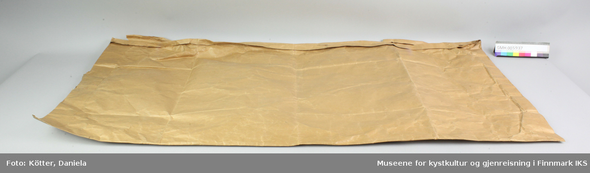 Papirposen er laget av brun papir og har en åpning på langside. Den har påført en etikett og har kostet 1,40 kroner.