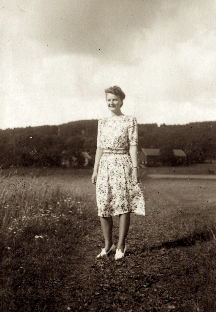 Ingrid Andersson (1918 - 2001, gift Skansing) står på en grusväg cirka 1940. Gården Livered "Majas" ses i bakgrunden.