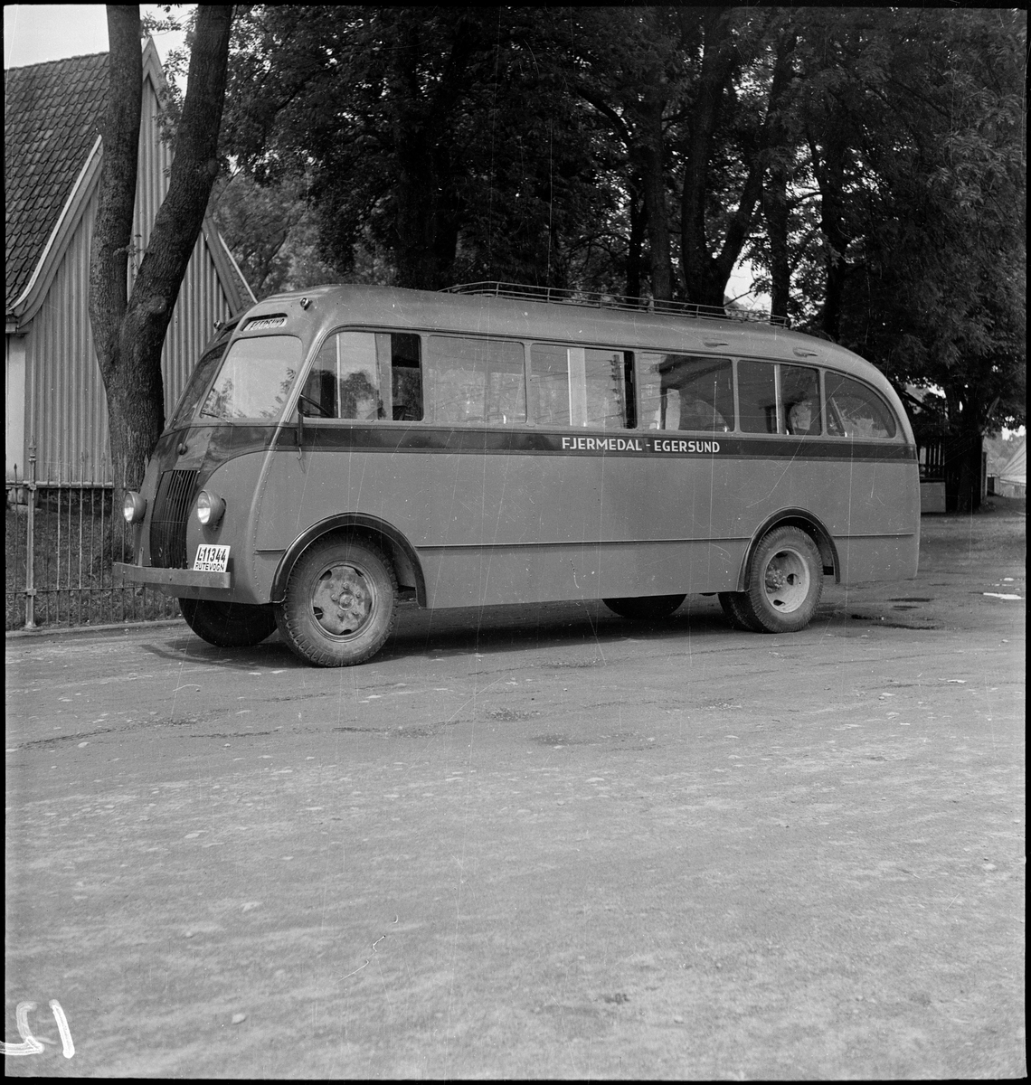 En buss på Egersund rutebilstasjon med Egersund kirke i bakgrunnen. Bussen gikk i ruta Fjermedal - Egersund.