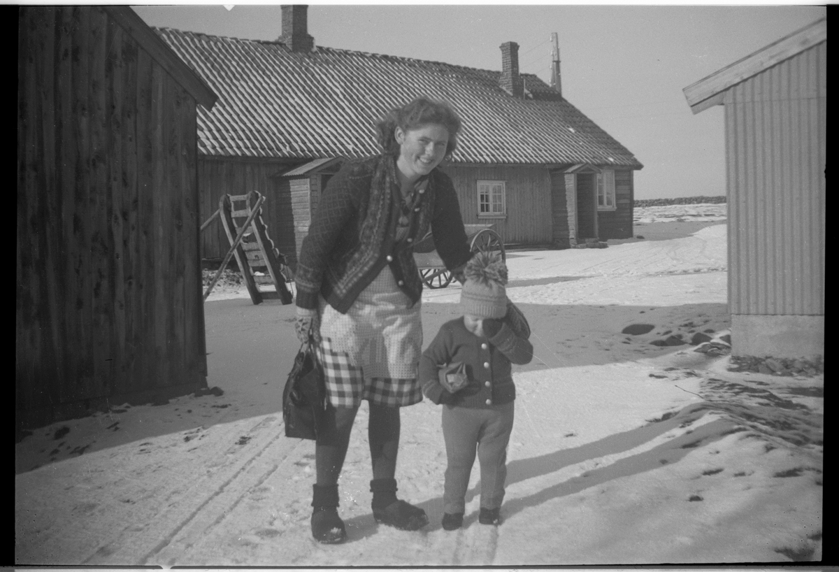 En kvinne med et lite barn på et gårdstun en vinterdag.