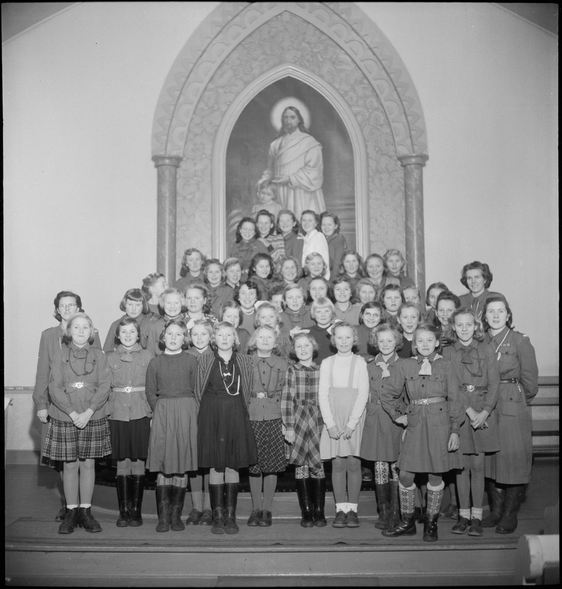 En  jentegruppe foran altertavlen i Metodistkirken.