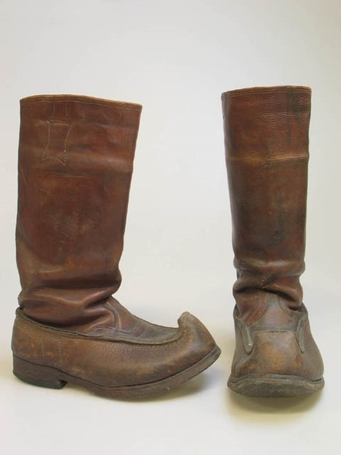 Ett par näbbstövlar av läder. Stövlarna är skurna och ihopsydda så att framändan bildar en näbb. Den vänstra skon är lappad med rött skinn. Skorna är från före andra världskriget. Näbbstövlar var vanliga under tiden före andra världskriget, de var inte speciellt varma men man kunde stoppa dem med hö för att få värme. På 1970-talet blev näbbstövlar populära hos kvinnor.
Givaren har använt skorna när han varit tomte för sin son och sina barnbarn.